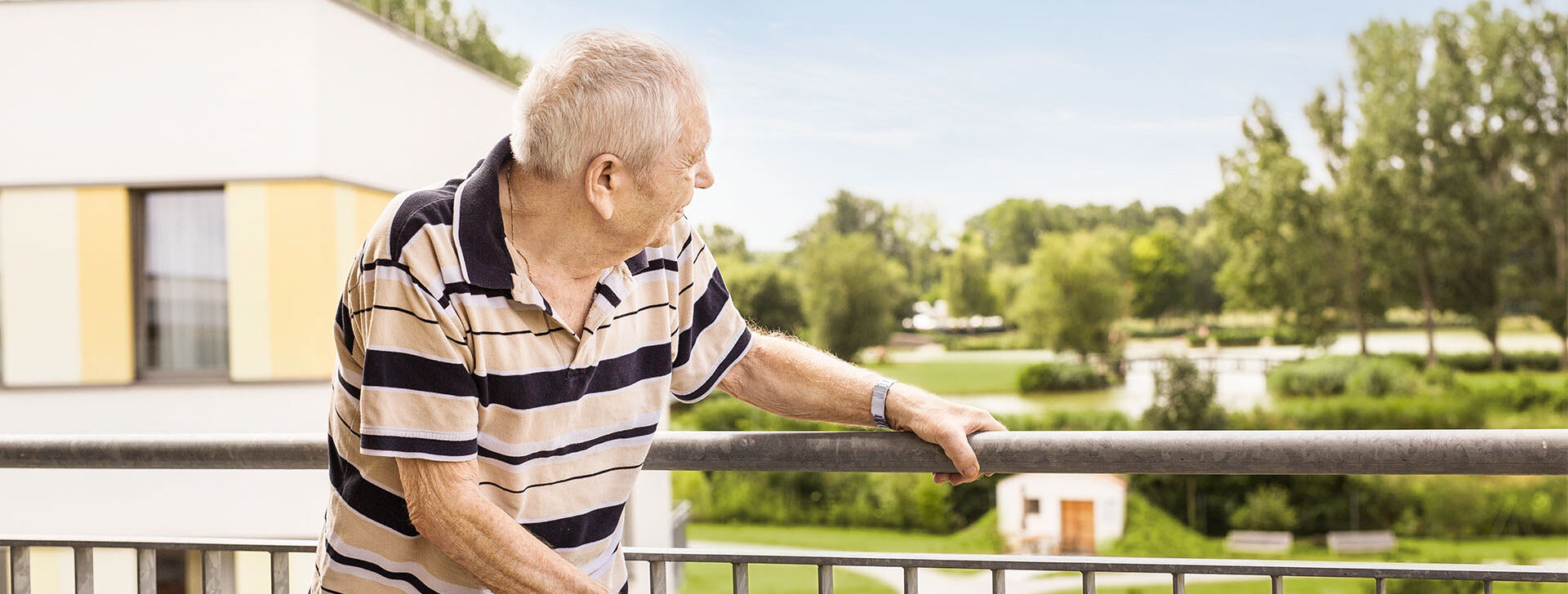 Ein Bewohner schaut vom Balkon ins Grüne.
