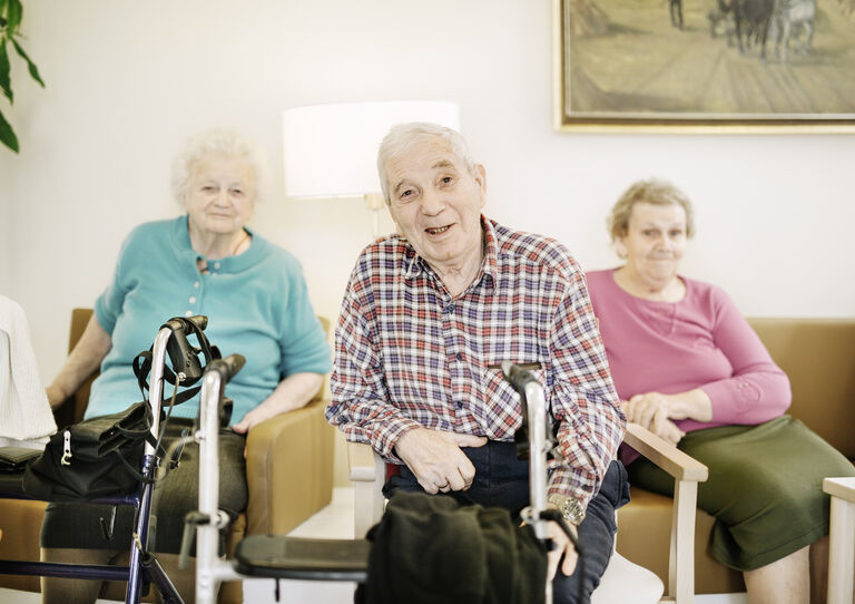 Zwei Bewohnerinnen und ein Bewohner des Urbanusheims in einer Sitzecke.