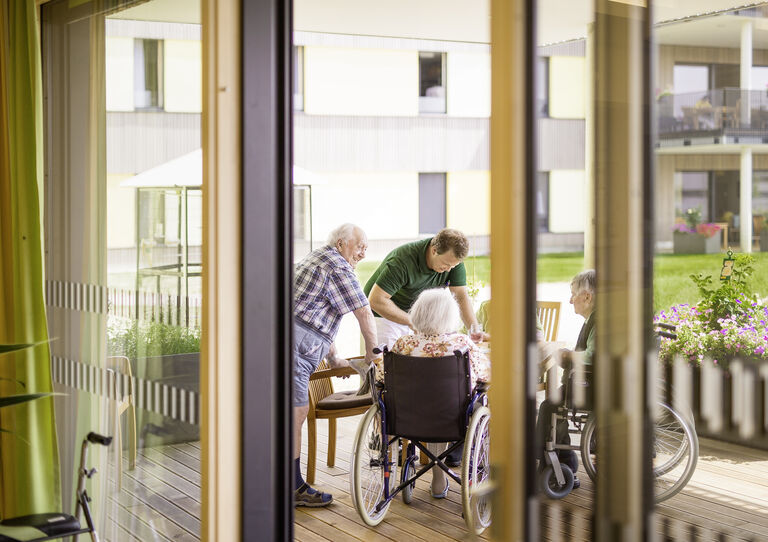 Drei Bewohner und ein Pfleger haben unterhalten sich auf der Terrasse.