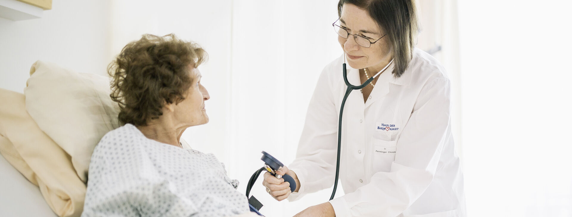 Eine Ärztin untersucht eine Bewohnerin mit einem Stethoskop.